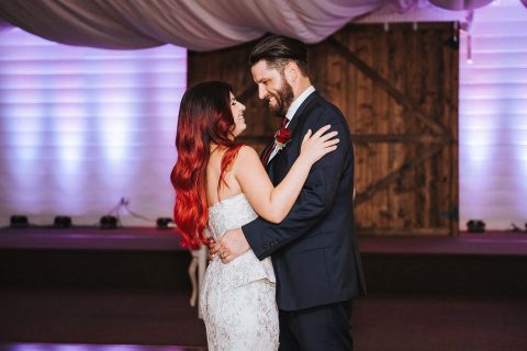 Hochzeitswahn - Ein strahlendes Paar tanzt innig, das rote Haar der Braut fällt herab, während sie sich zärtlich umarmen, und ihr Hochzeitskleid glänzt im warmen, stimmungsvollen Licht.