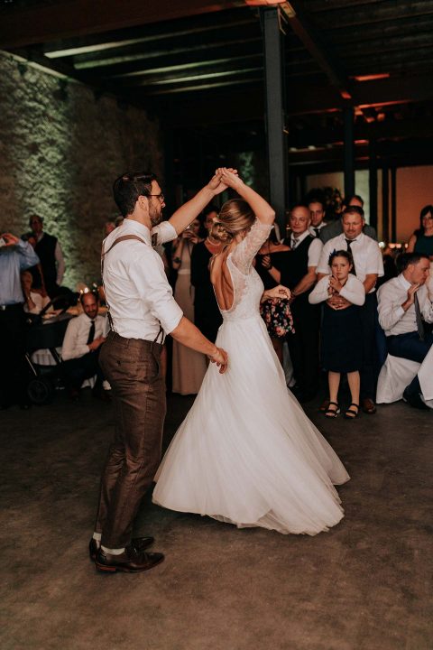 Hochzeitswahn - Ein Paar im Hochzeitskleid tanzt vor den Augen der Gäste einen romantischen ersten Tanz bei stimmungsvollem Licht und fängt damit einen Moment der Liebe und des Feierns ein.