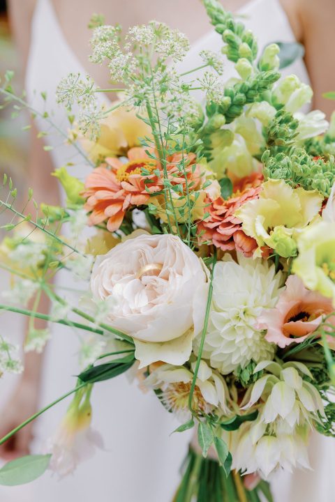 Hochzeitswahn - Eine Braut hält einen Strauß grüner und weißer Blumen.