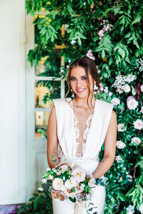 Hochzeitswahn - Eine Braut im weißen Overall posiert vor einer grünen Wand.