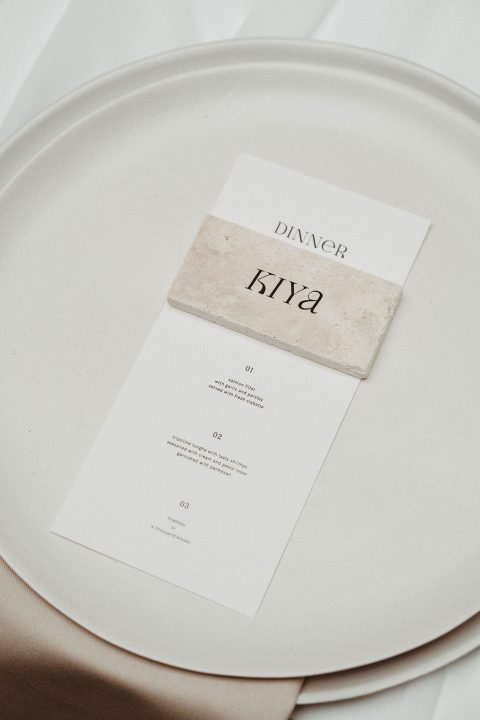 Hochzeitswahn - Ein elegantes Abendmenü auf einem feinen Keramikteller mit minimalistischem Design und einer dezenten Marmorsteinklammer, das an ein anspruchsvolles Dinner-Event erinnert.